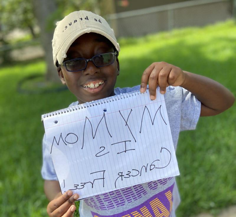 Brittany Clayborne's son, Micah, holding a sign that says his mom is cancer-free. (Photo courtesy of Brittany Clayborne)